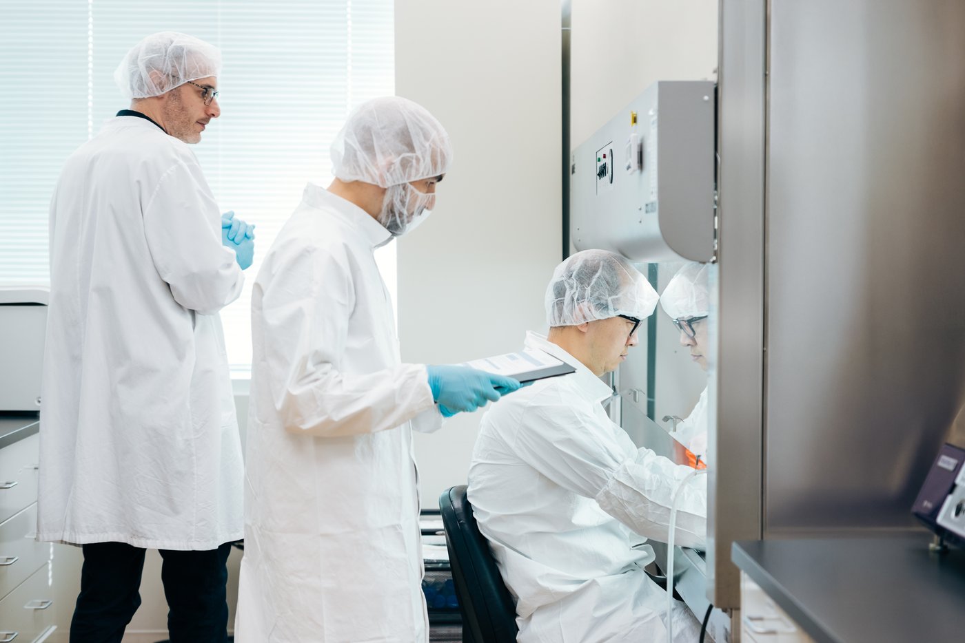 Gowned trainees working at a cleanroom bench with lab instrumentation during CATTI hands-on training